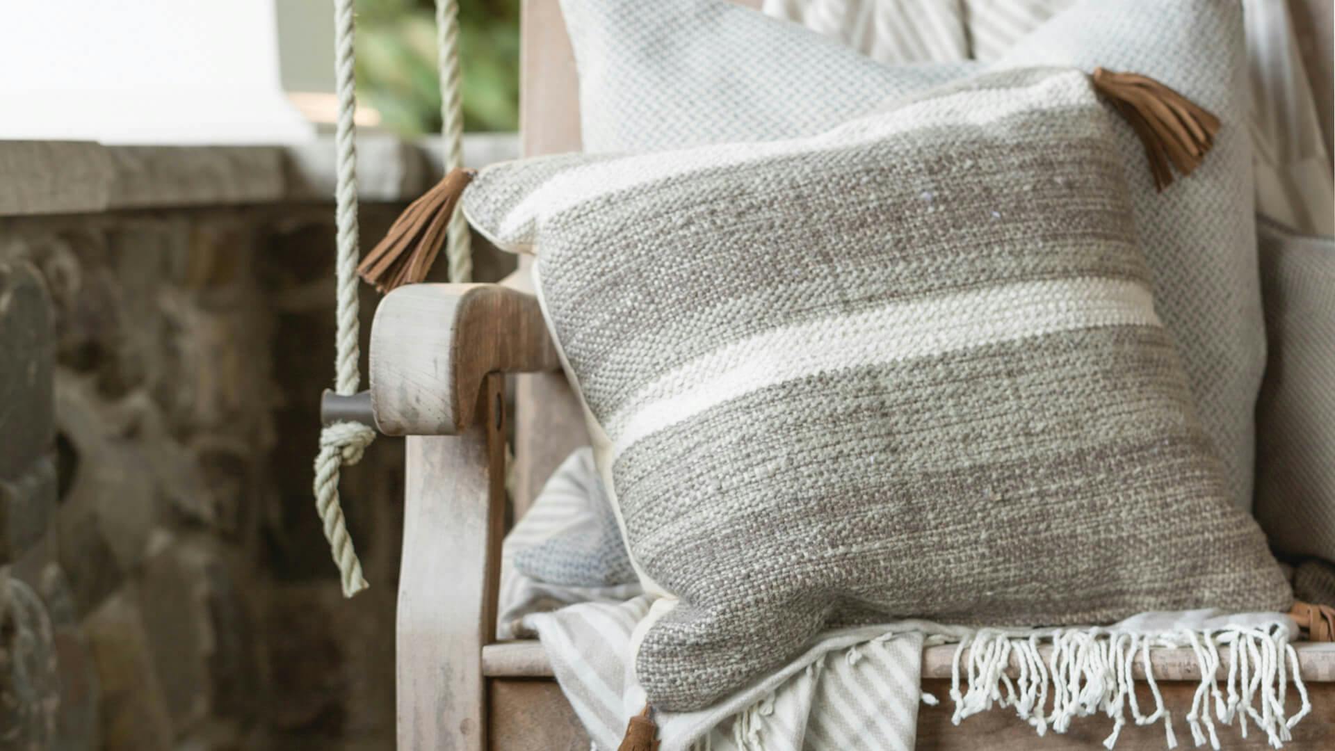 Closeup of a pillow and blanket on a wooden porch swing