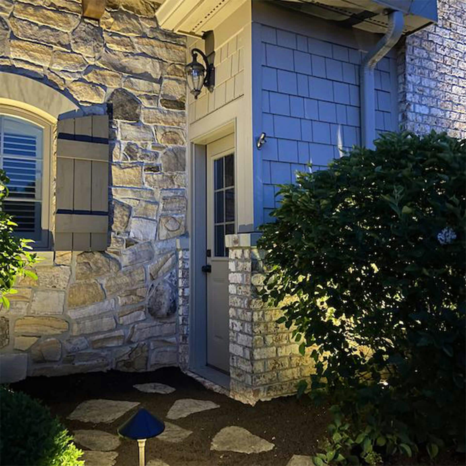 View of exterior entryway to home at dusk, exterior lighting and path lighting is on.